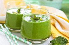 two glasses filled with green smoothie on top of a table