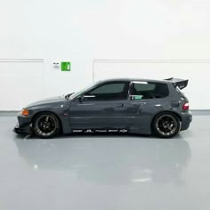 a grey car parked in a garage next to a white wall