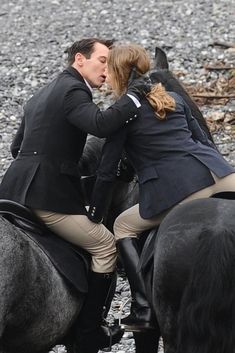 a man and woman riding on the backs of horses