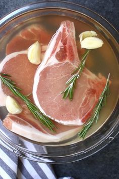 two raw meats in a glass bowl with rosemary garnish