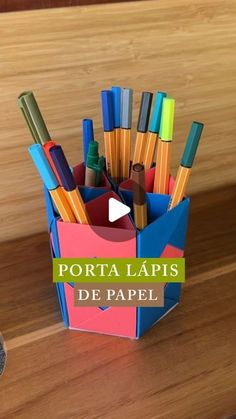 a cup full of pens and pencils sitting on top of a wooden table with the words porta lapis de papel