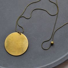 Minimalist brass necklace with circle pendant. The delicate brass snake chain without clasp is simply pulled over the head and is adorned by an approximately 4cm circle pendant made of matte polished brass. A simple hand charm that goes with any outfit. I will gladly make you a different length, just send me a message. Details - brass  - approx. 78cm long - Pendant: approx. 4cm diameter Info Brass is an alloy of copper and zinc. When tarnished, it can be restored to a high shine with a simple me Minimalist Brass Jewelry With Large Pendant, Everyday Circular Brass Necklace, Everyday Brass Necklace, Round Brass Necklace With Moon Charm, Everyday Brass Round Necklace, Brass Moon Charm Round Necklace, Brass Moon Charm Necklace, Everyday Round Brass Necklace, Brass Circle Necklace For Gifts