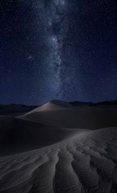 the night sky is filled with stars above sand dunes