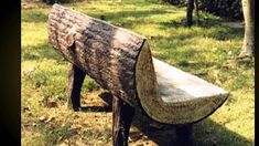 a wooden bench sitting on top of a lush green field next to a tree trunk