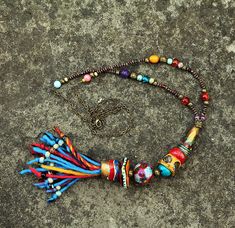 a multicolored beaded necklace with tassels and beads hanging from it