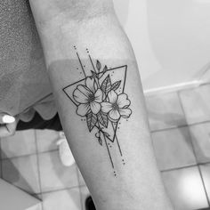 a black and white photo of a flower tattoo on the left arm with geometric shapes in the background