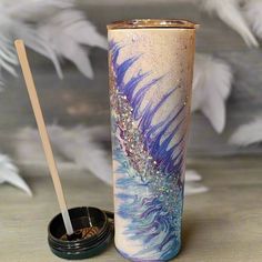 a cup with a straw in it sitting on a table next to some white feathers