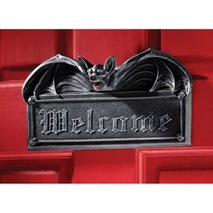 a black metal sign with a bat on it's side hanging from a red door