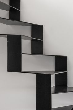 a black and white photo of some bookshelves in the shape of stairs with one person walking up it