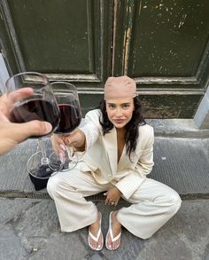 a woman sitting on the steps holding a glass of wine and looking at someone's hand