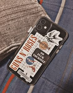 a cell phone case sitting on top of a pair of jeans with patches and stickers