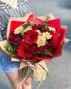 a woman holding a bouquet of red and white flowers