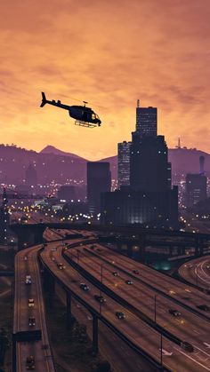 a helicopter flying over a highway at night with city lights in the backgroud