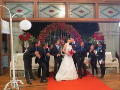 the bride and groom are standing in front of their wedding party on the red carpet