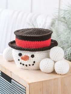 a crocheted snowman sitting on top of a wooden table