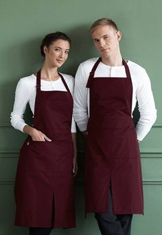 two people standing next to each other wearing brown aprons