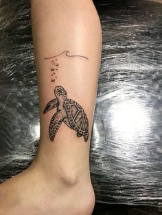 a small turtle tattoo on the ankle with bubbles coming out of its mouth and an ocean wave behind it