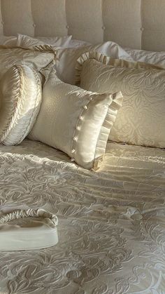 a white bed with pillows on top of it and a pillow case in the middle