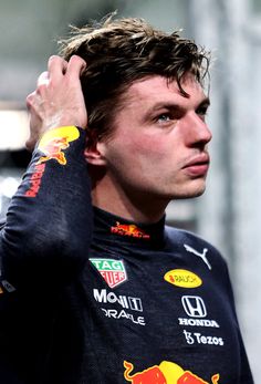 a close up of a person wearing a red bull shirt and holding his hand to his head