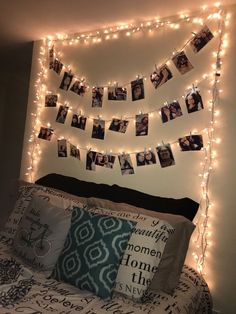 a bed topped with lots of lights and pictures hanging on the wall above it's headboard