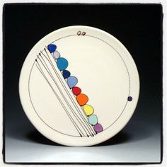 a white plate with multicolored lines and balls painted on it's side