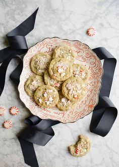 a plate full of cookies and candy canes on a marble table with black ribbon