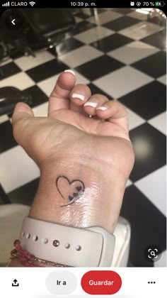 a woman's wrist with a heart tattoo on it