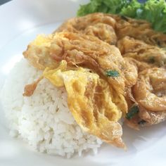 a white plate topped with rice and fried chicken next to broccoli on top of it