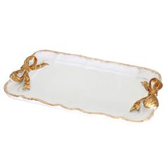 a white and gold serving tray with bows on the handles, sitting on a white surface