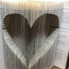 an open book with pages folded in the shape of a heart