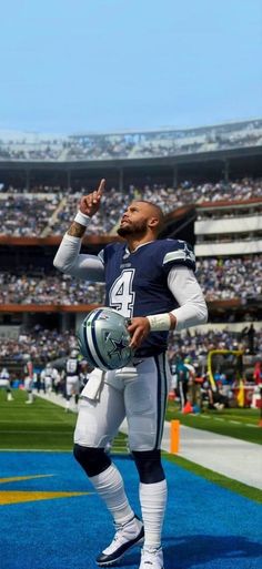 a football player is standing on the field with his hand up in the air while holding a ball