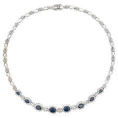 This stunning blue sapphire and diamond necklace is sure to turn heads. Made with 8 oval sapphires surrounded by diamond halos, the sapphires weigh 6.32 carats. Altogether the necklace has 167 diamonds. The diamonds are G-H, SI and weigh 1.08 carats. The necklace weighs 32.1 grams. The necklace is stamped "18K". The necklace is vintage in very good condition. Necklace Specifications: Metal: 18k White Gold Sapphire Count: 8 Sapphire Shape: Oval Diamond Count: 167 Diamond Weight: 1.08 carats Diamo Formal Blue Oval Diamond Necklace, Blue Oval Diamond Necklace In Fine Jewelry Style, Blue Oval Diamond Necklace Fine Jewelry, Oval Sapphire Necklace With Halo Setting, Oval Sapphire Diamond Necklace, Blue Oval Jewelry With Pave Setting, Elegant Blue Necklace With Pave Setting, Elegant Blue Necklaces With Pave Setting, Sapphire Diamond Necklace