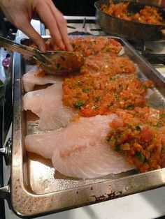 someone is cutting up some fish on a metal tray in front of other food items