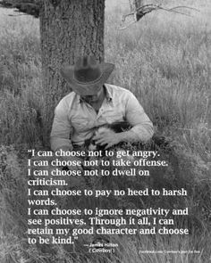 a man with a cowboy hat sitting in the grass next to a tree and holding a cat