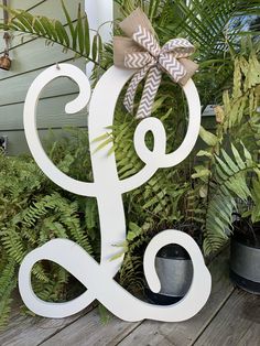 a wooden sign with a bow on it sitting in front of some potted plants