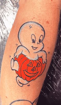 a person with a ghost tattoo on their arm holding a jack - o'- lantern