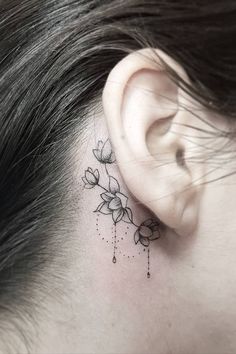 a woman's behind the ear has a small flower tattoo on her left side