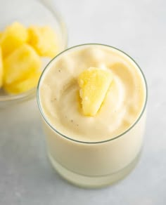 a glass filled with pudding next to a bowl full of sliced pineapples on the side