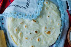 two tortillas are on a blue and white cloth with a wooden utensil