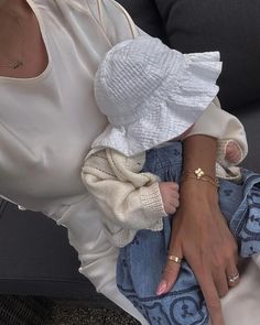 a woman holding a baby in her lap while wearing a white shirt and blue jeans