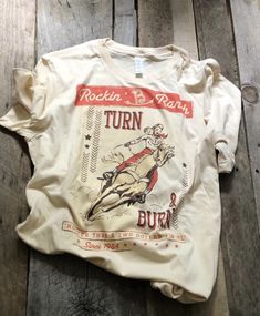 Rockin' B Ranch "Turn and Burn" Graphic Tee - Original Cowgirl Clothing Co - Inspired by vintage rodeo posters and cowgirl novels - Creamy natural color with orange accents - 100% Combed Spun Cotton and Ring-Spun Cotton Rodeo Poster, Western Girl Outfits, Cowgirl Clothing, Cute Cowgirl Outfits, Rodeo Events, Country Tees, Country Style Outfits, Western Graphic Tees, Western Style Outfits