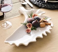 a plate with figs and nuts on it next to a glass of wine