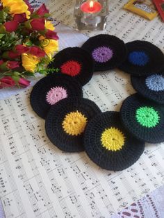 six crocheted coasters sitting on top of a table next to a bouquet of flowers