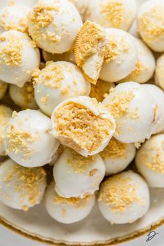 a white plate topped with yellow oreo truffles covered in powdered sugar