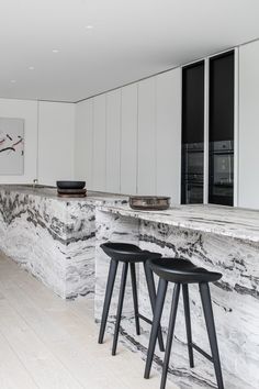 a kitchen with marble counter tops and stools