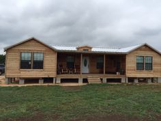 a wooden house sitting on top of a lush green field