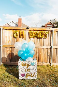 a baby's first birthday party with balloons and streamers on the grass in front of a fence