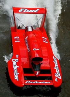 a red boat with white lettering on it is going through the water and splashing around