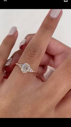 a woman's hand holding an engagement ring with a diamond on it and two fingers