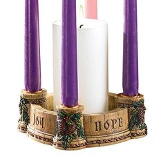 three purple candles sitting on top of a wooden stand with pine cones and holly wreaths